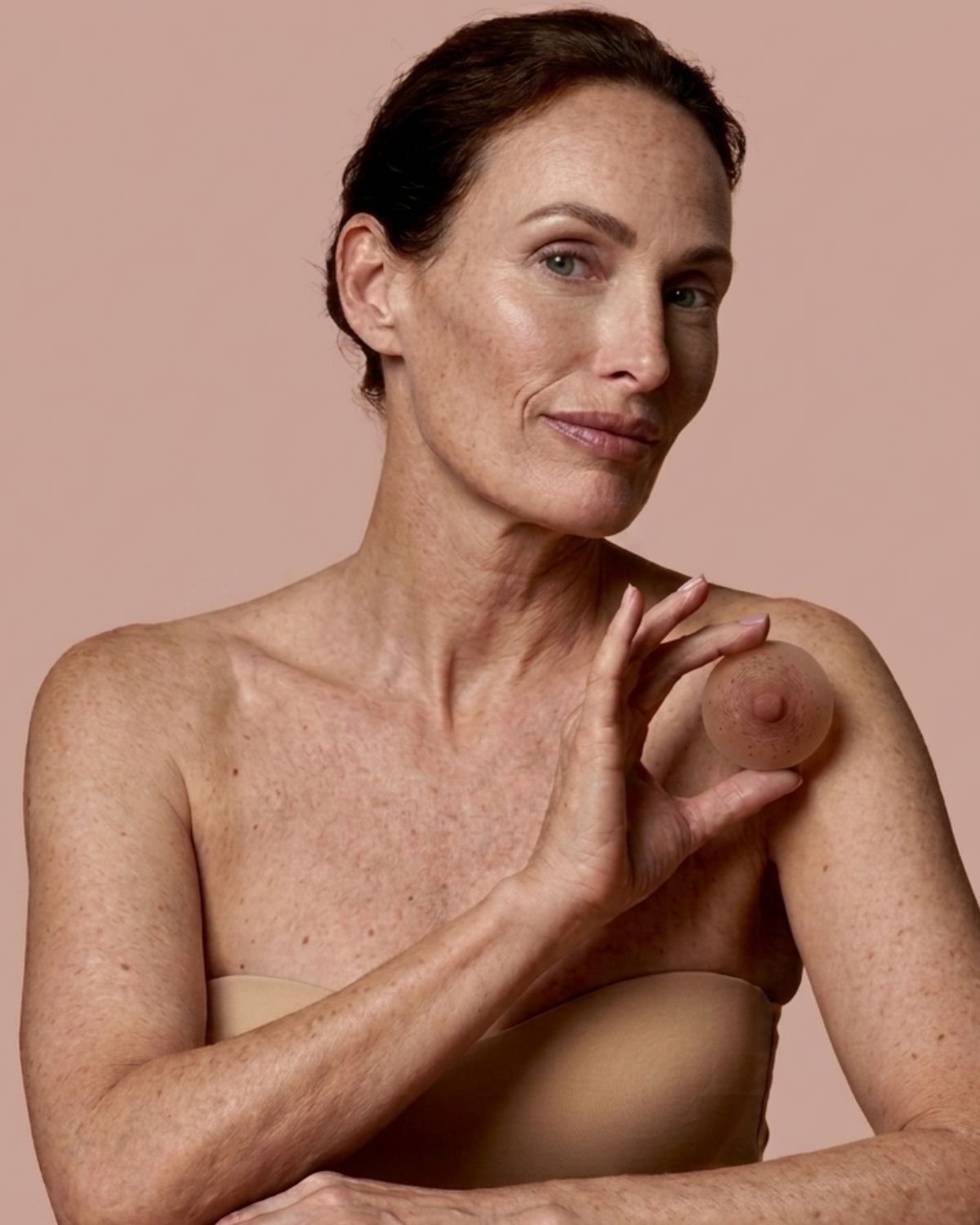 Retrato editorial de una persona sosteniendo una prótesis de areola y pezón